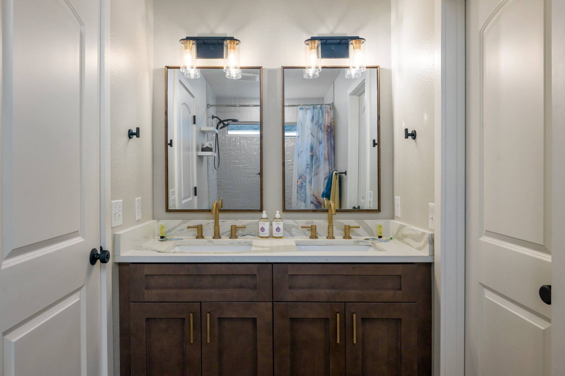 A bathroom with a double vanity, two sinks, and a large mirror with lights.