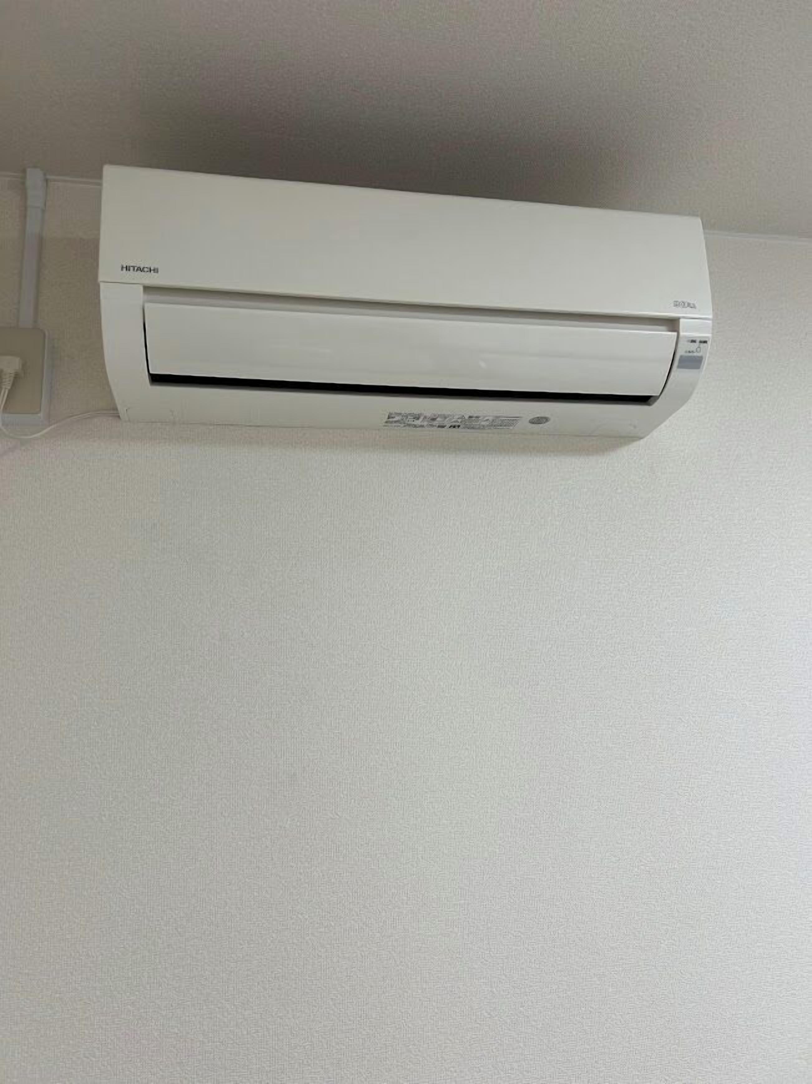 Un aire acondicionado blanco montado en la pared, con el nombre de la marca "HITACHI" visible en la esquina superior izquierda.