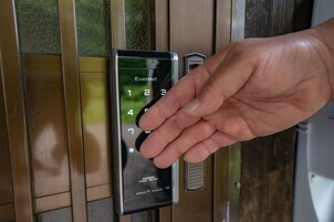 A hand interacting with a keypad door lock.