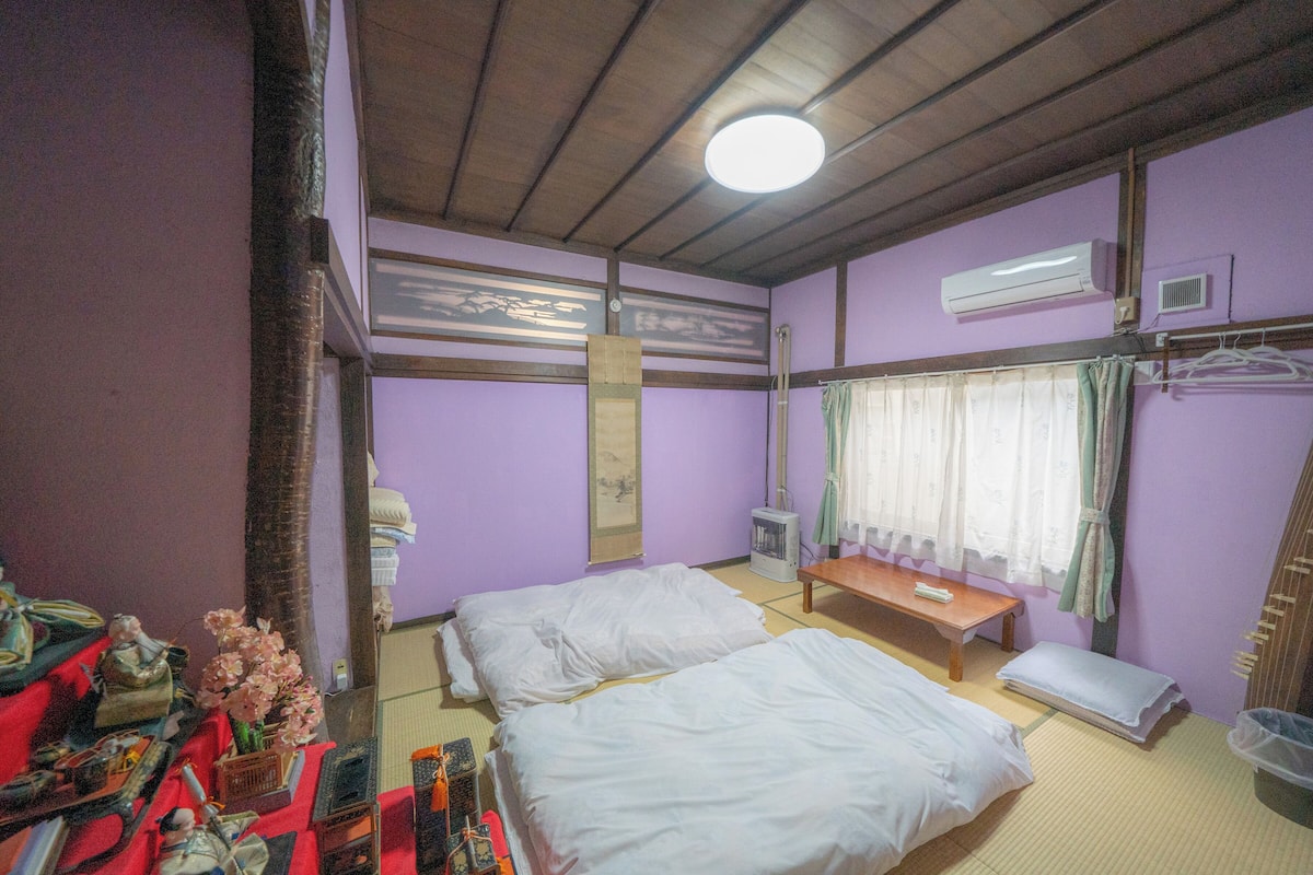A room with two beds, a wooden bench, a small table, and a mirror.