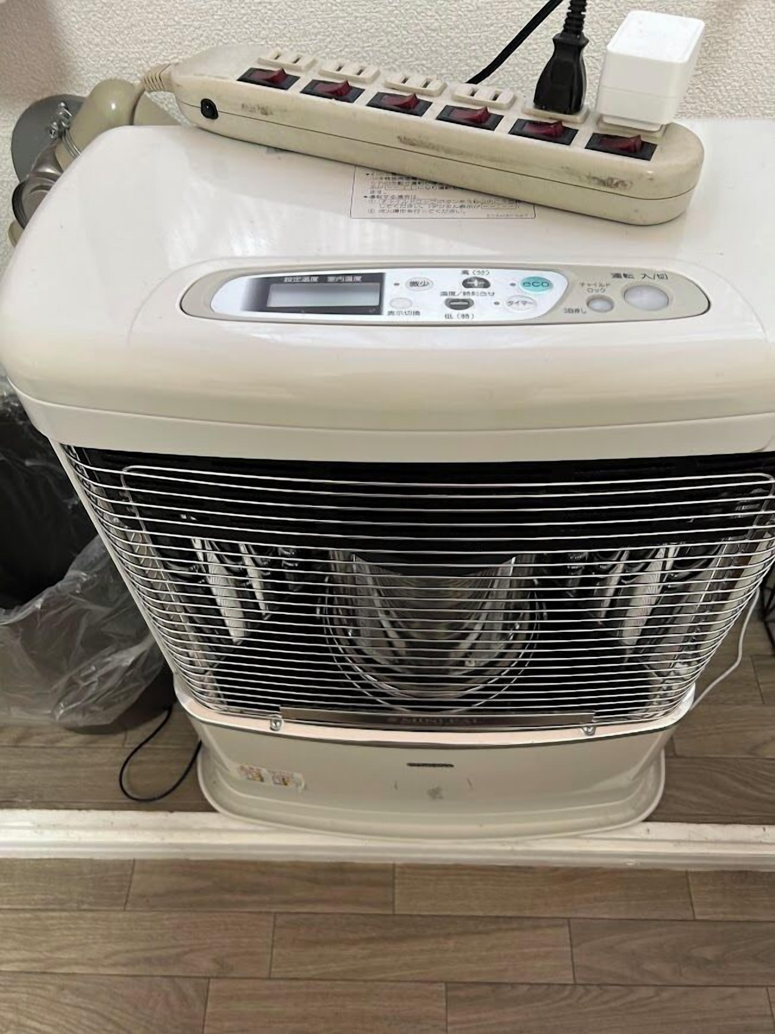 A white portable heater with a digital display and control buttons, placed on a white surface.