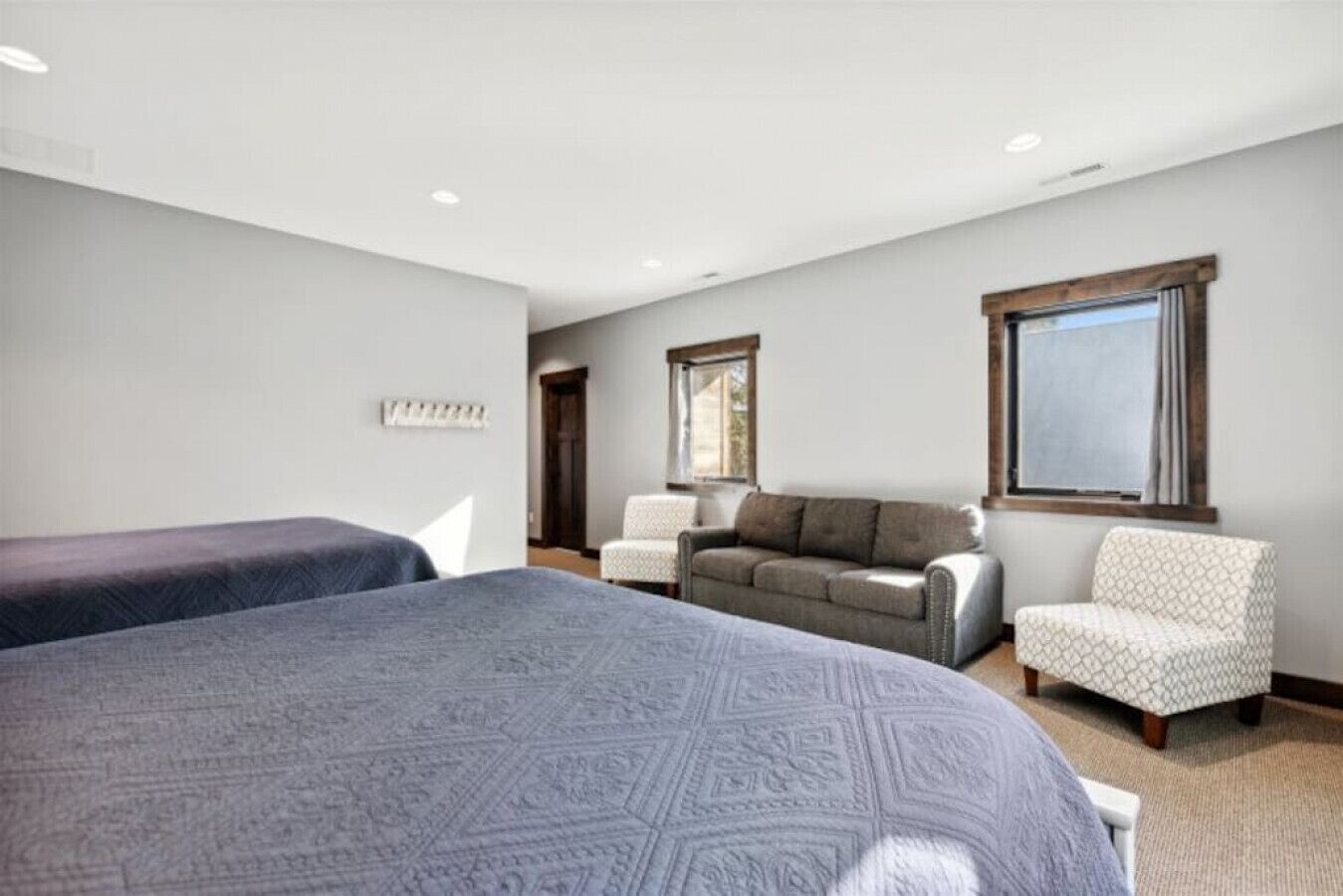 A hotel room with two beds, a sofa, a chair, and a window.