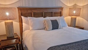 A neatly made bed with white linens and a patterned throw blanket, flanked by two bedside tables with lamps. - Roberts Beach Escape in Tairua is 3-5 minute walk from the beach (Tairua)