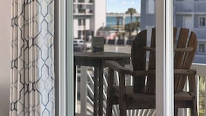 A wooden chair and table on a balcony with a view of a building and a sign.