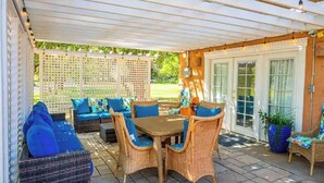 A covered patio area with wicker furniture, a table, and chairs.