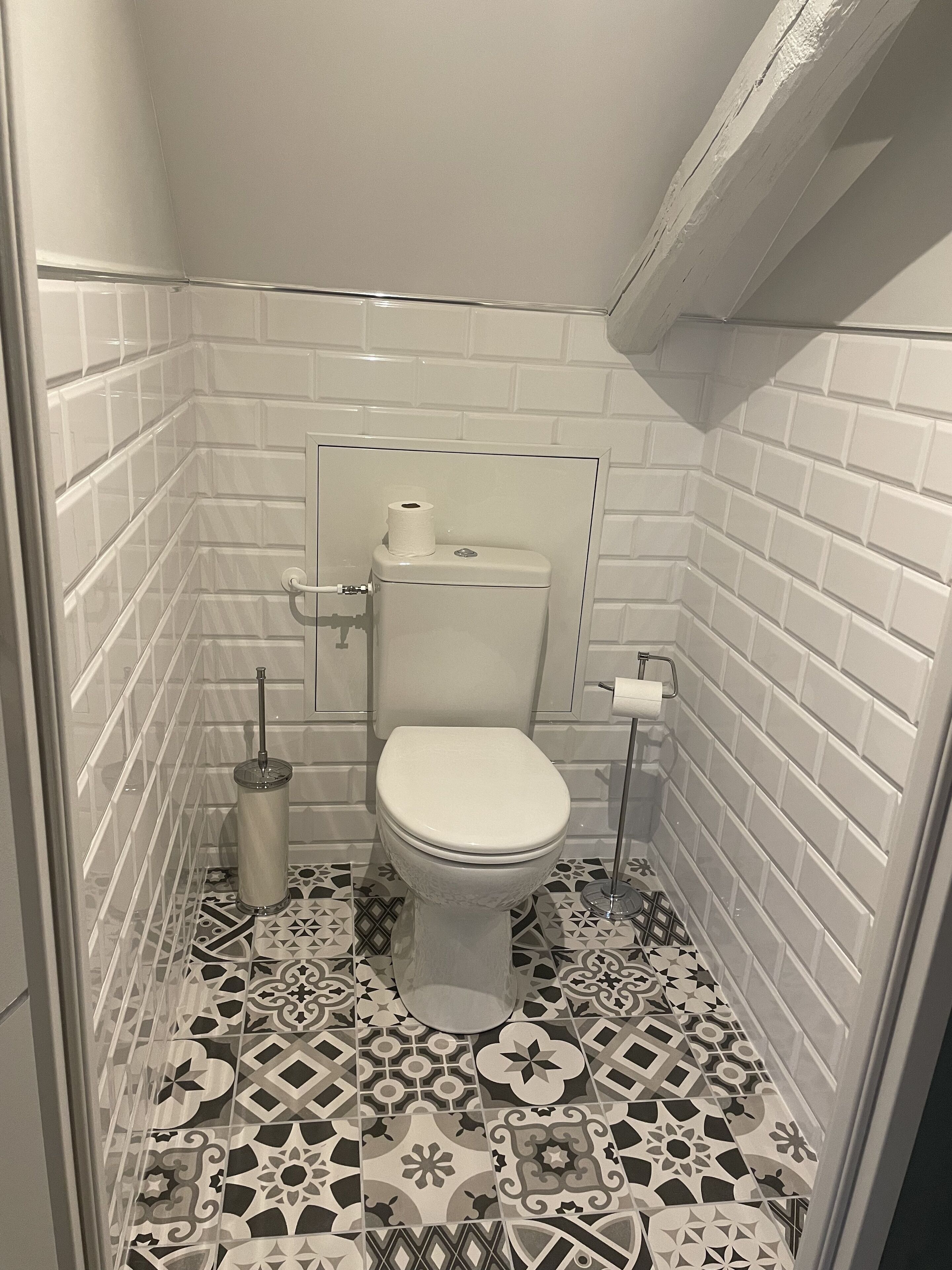 A small, tiled bathroom with a toilet, a toilet paper holder, and a bidet.