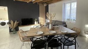 A dining area with a wooden table, black chairs, and a TV in the background.