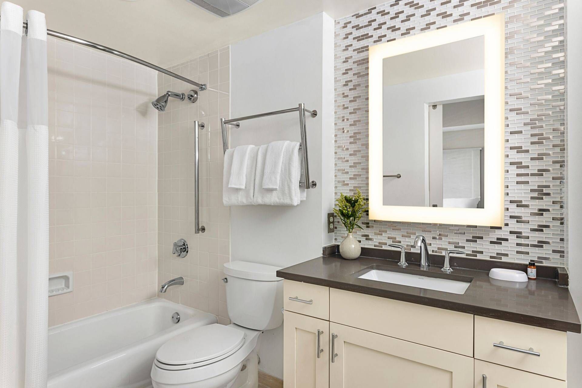 Une salle de bain moderne équipée d’une douche, de toilettes et d’un meuble-lavabo avec un miroir.