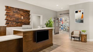 A reception desk with a wooden backdrop, a laptop, and a flat-screen TV.