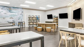 A classroom with tables, chairs, a bookshelf, and a mural on the wall.