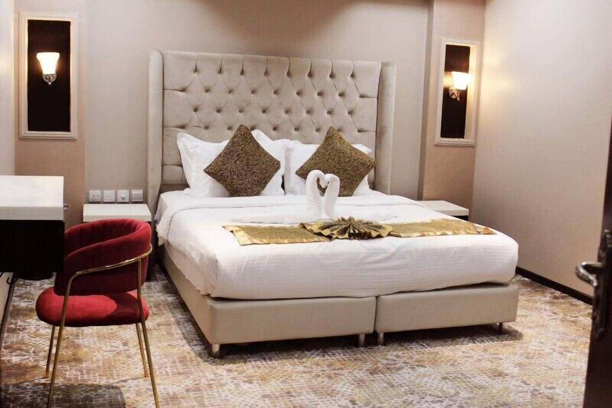 A hotel room with a large bed, a desk, and a red chair.