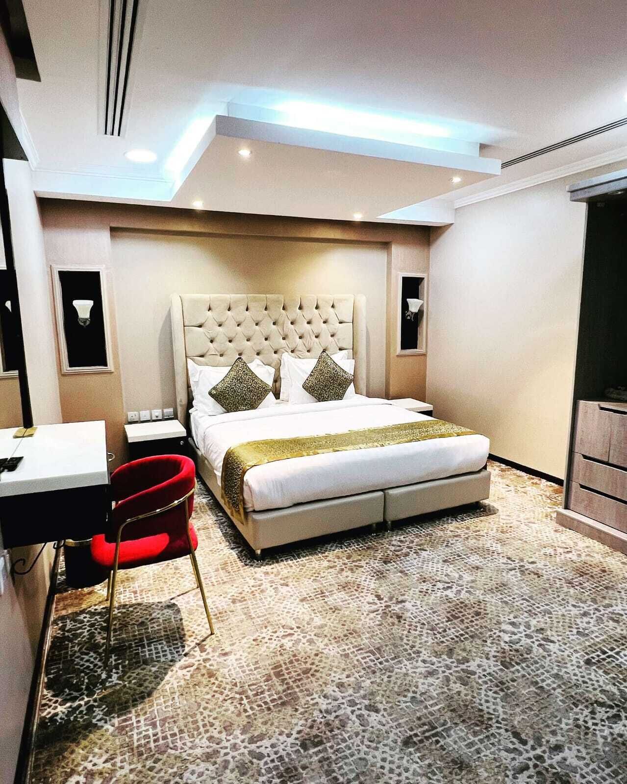 A modern hotel room with a large bed, a desk, and a red chair.