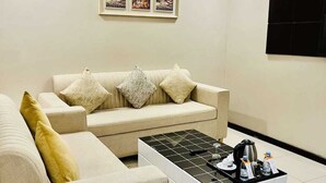 Un salon moderne avec un ensemble de canapés de couleur beige, une table basse et un téléviseur fixé au mur.