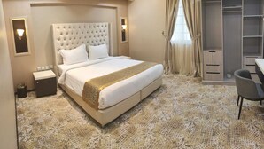 Une chambre d’hôtel avec un grand lit, un bureau et une armoire.