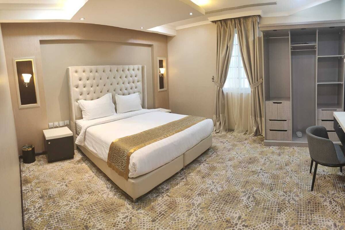 A hotel room with a large bed, a desk, and a wardrobe.