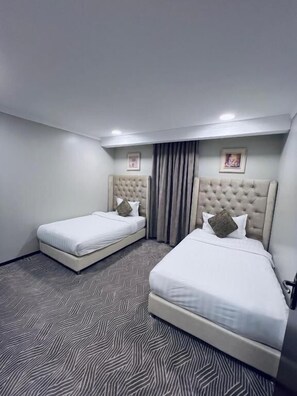 A hotel room with two beds, a patterned carpet, and a framed picture on the wall. - Asala AL Shorouk Serviced Apartments (Al Khobar)