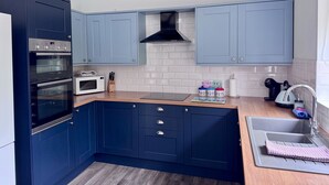 A modern kitchen with dark blue cabinets, a built-in oven, microwave, and a stainless steel sink. - The Long Barn, Brick Kiln Barns, Dilham - Sleeps 6 in Luxury - Dog Friendly (Dilham)