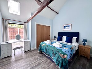 Quarto com cama, escrivaninha, espelho e guarda-roupa.