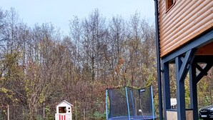 A wooden playhouse with a slide and a trampoline in a backyard. - ART House Transylvania Sibiu (Avrig)