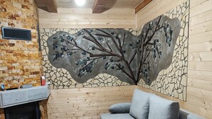 A cozy room with a fireplace, a gray sofa, and a mosaic wall. - ART House Transylvania Sibiu (Avrig)