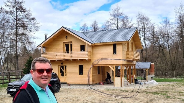 A two-story wooden house with a balcony, a covered porch, and a car parked in front. - ART House Transylvania Sibiu (Avrig)