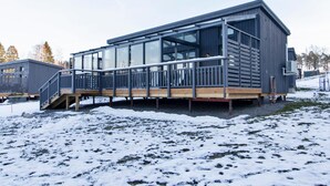 Ein modernes Gebäude mit großen Fenstern, einer Holzdachterrasse und einem Metallgeländer.