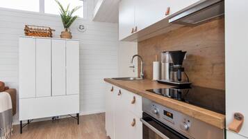 A modern kitchen with white cabinetry, a wooden countertop, a coffee maker, and a built-in oven.