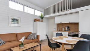Ein modernes Wohnzimmer mit einem braunen Sofa, einem Couchtisch und einem Essbereich mit einem runden Tisch und Stühlen.