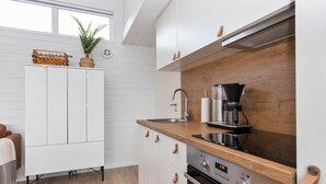 Eine moderne Küche mit weißen Schränken, einer Holz Arbeitsplatte, einer Kaffeemaschine und einem eingebauten Backofen.