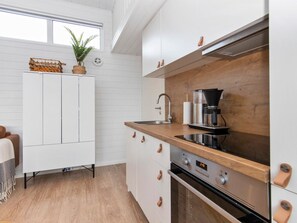 Een koelkast, een magnetron, een vaatwasser, kookgerei, borden en bestek