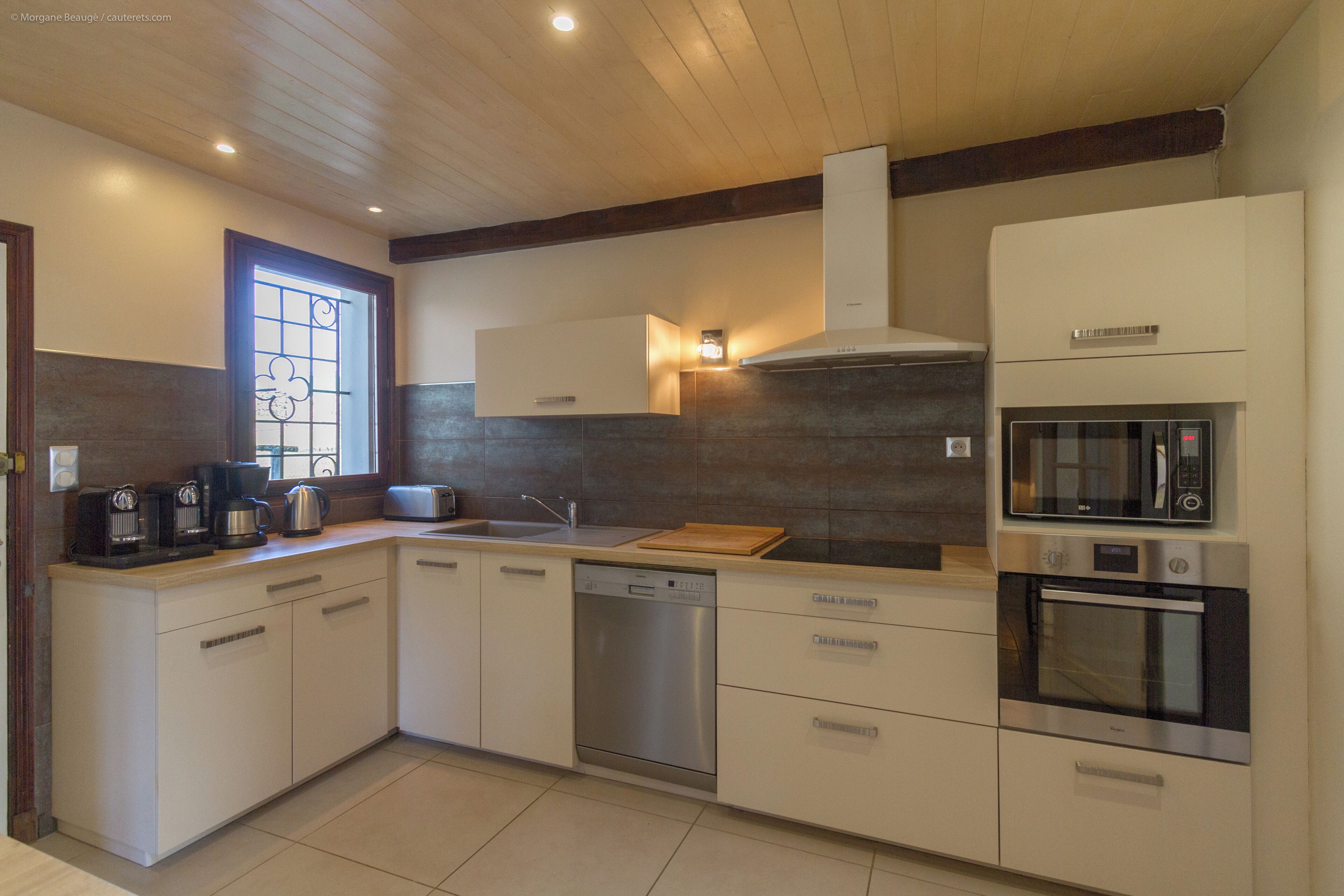 A modern kitchen with white cabinetry, a dishwasher, a microwave, and an oven.
