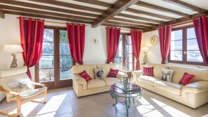 A living room with a beige sofa set, a glass coffee table, and red curtains.