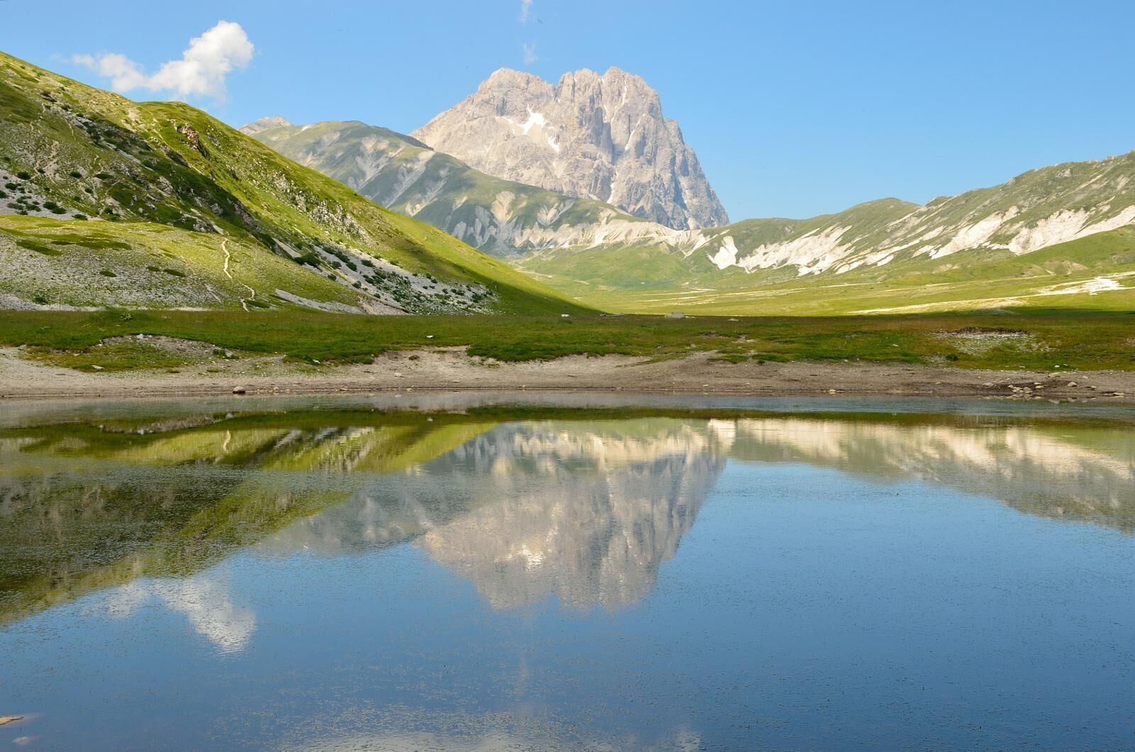 Un paysage de montagne avec un lac aux eaux limpides qui reflète le paysage environnant.