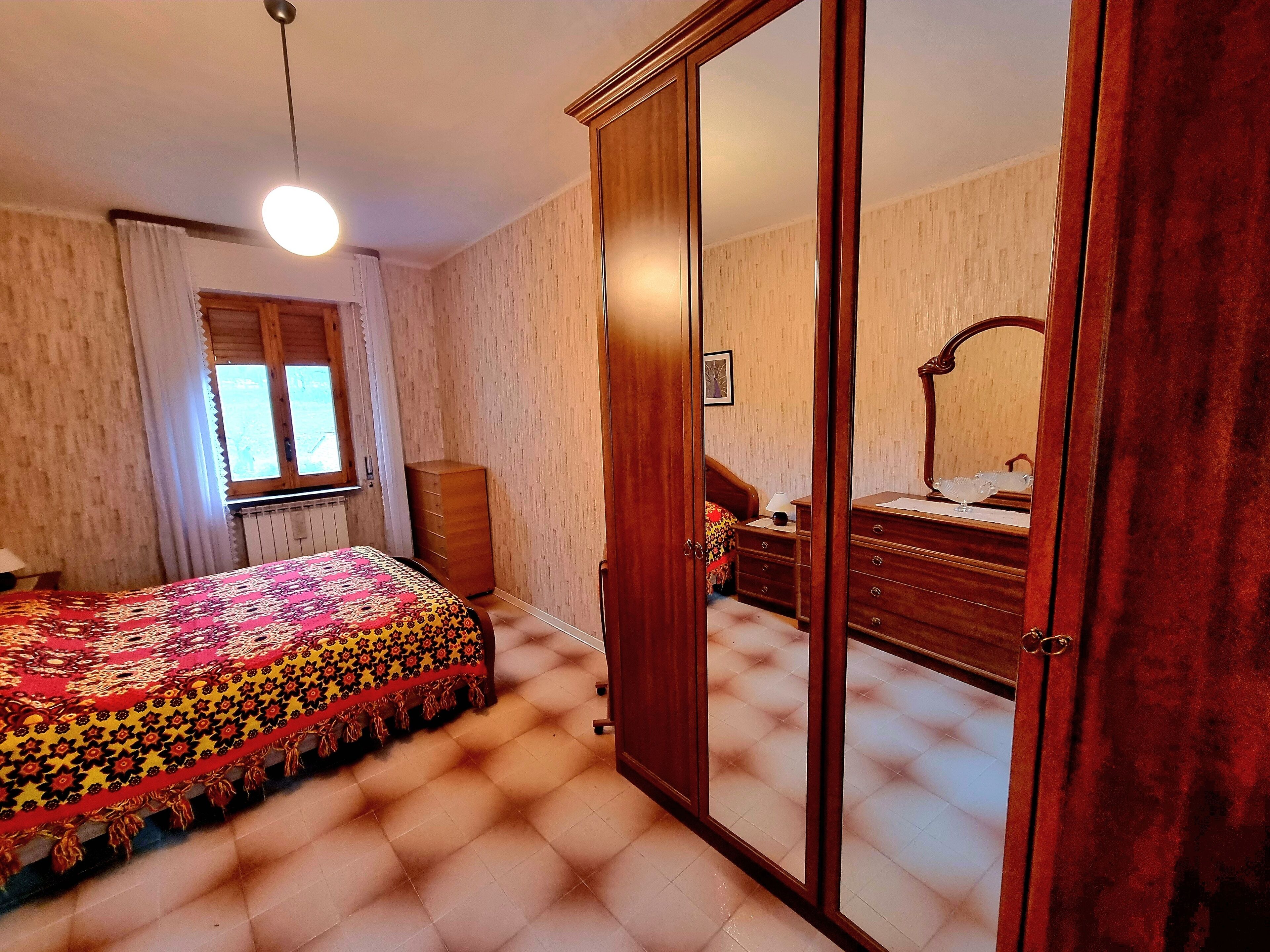 A bedroom with a bed, a dresser, a mirror, and a wardrobe.