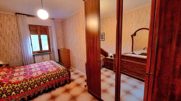 A bedroom with a bed, a dresser, a mirror, and a wardrobe.