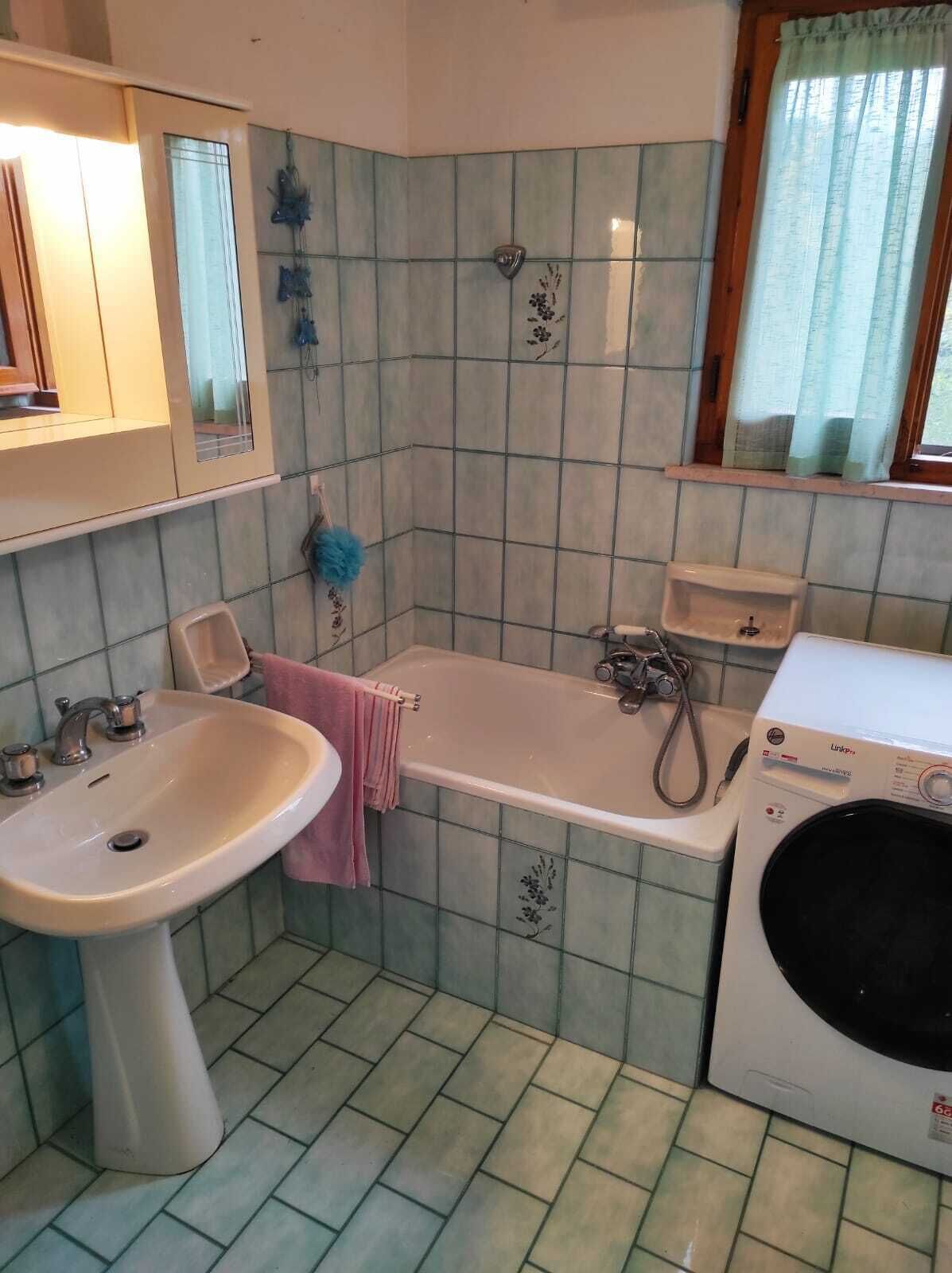 Casa de banho com lavatório, banheira e máquina de lavar roupa.
