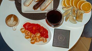Une table où sont présentés divers aliments, notamment des pâtisseries, des fruits et des boissons.