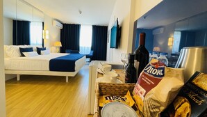 Een hotelkamer met een bed, een bureau, een eethoek en een keukenblad.