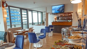 Een buffetgedeelte met diverse food stations, zitgelegenheden en een bar met uitzicht op zee.