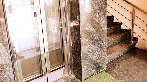 Un conjunto de puertas de cristal que dan a una escalera con pared de granito y barandilla de metal.