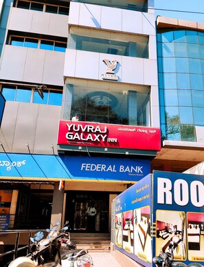 Een gebouw met een bord voor Yuvraj Galaxy Inn, een vestiging van Federal Bank, en een ROO hotel.