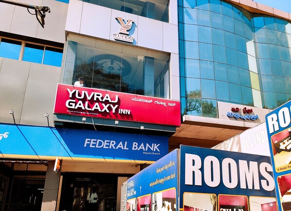 Een gebouw met een bord voor Yuvraj Galaxy Inn, een filiaal van Federal Bank, en een advertentie voor kamers.