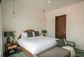 Relax in comfort with a large bed, bedside tables, and a chair, set against a clean, modern backdrop.