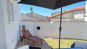 Ein Terrassenbereich im Freien mit Tisch, Stühlen, Sonnenschirm und Holzdeck.