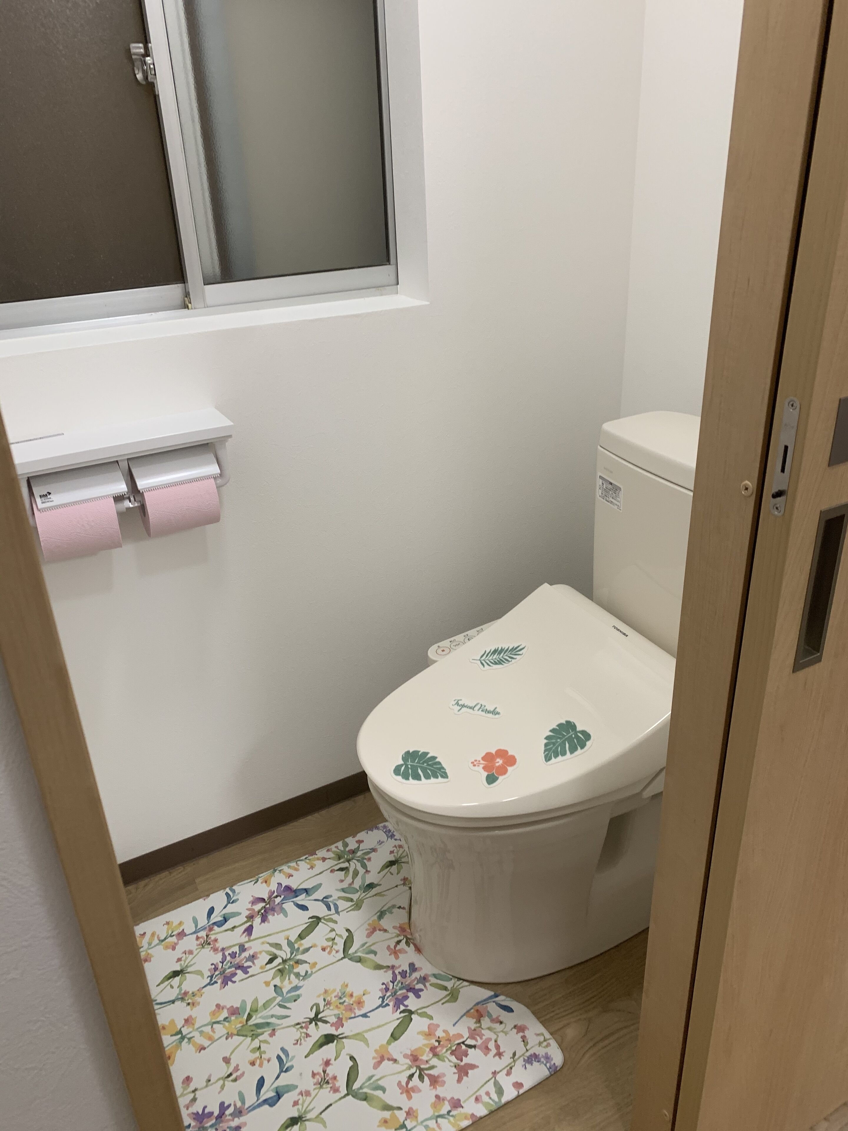 Un baño pequeño con inodoro, ventana y dispensador de papel higiénico.