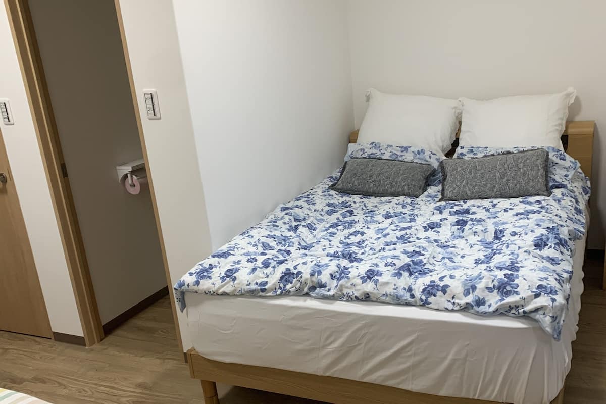 A bedroom with a wooden bed, white walls, and a wooden floor.