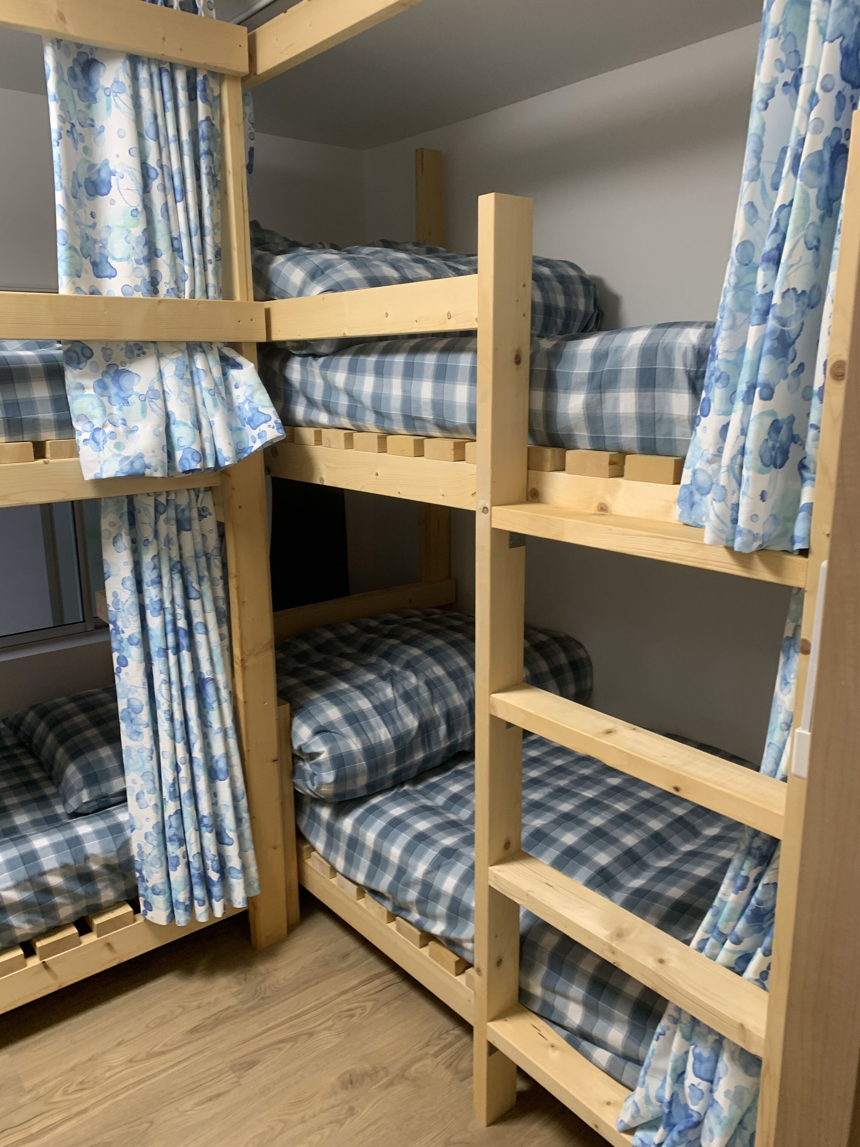 A bunk bed with blue and white checkered bedding, wooden frame, and matching curtains.