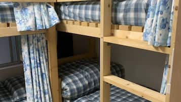 A bunk bed with blue and white checkered bedding, wooden frame, and matching curtains.