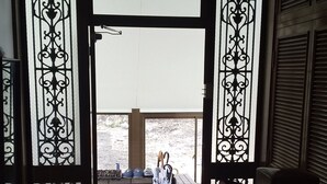 A view through a doorway with decorative metal grilles, leading to an outdoor area with a tiled floor and a bench. - Minpaku Ota Building No.2 (Otaru)