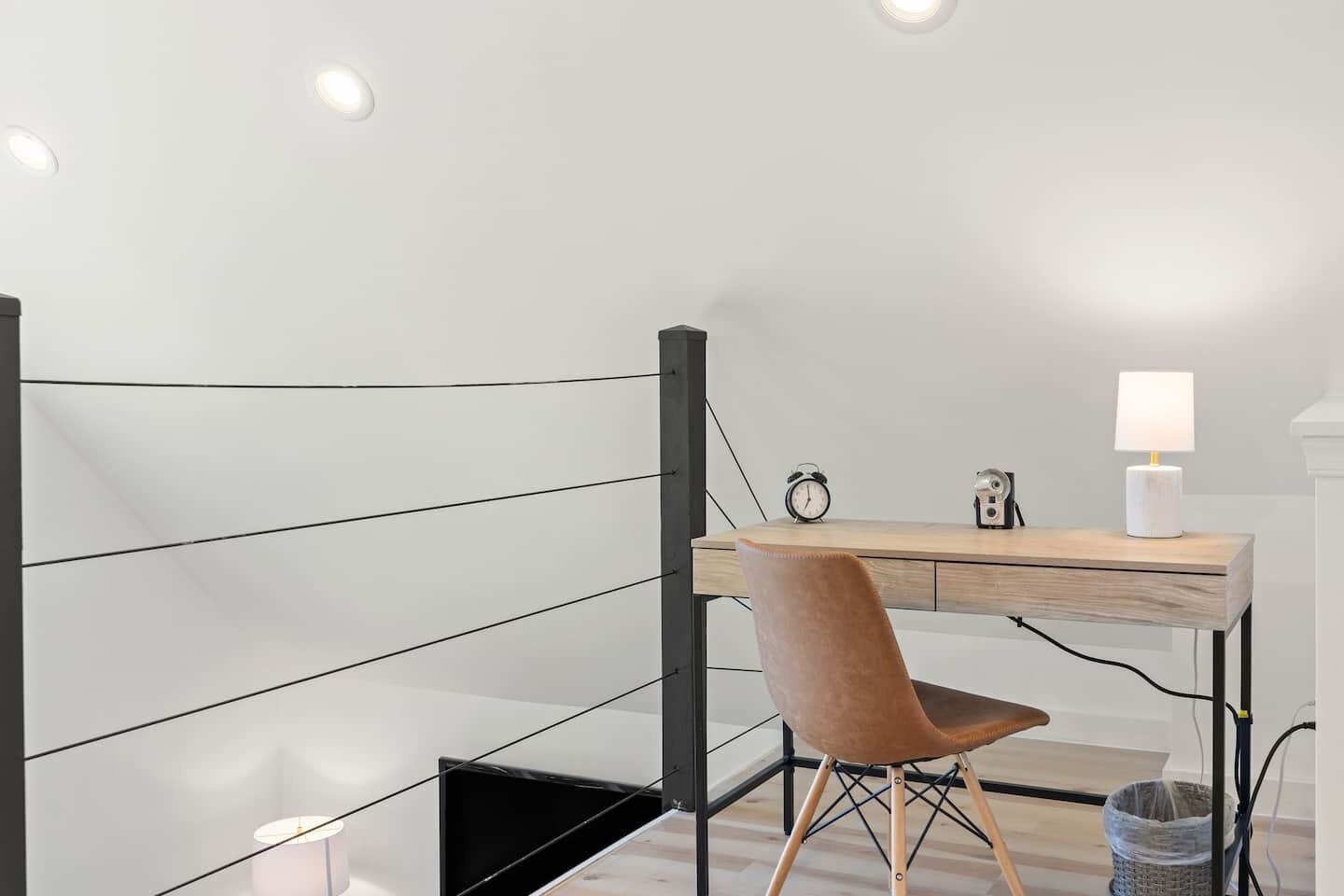 A modern workspace with a desk, chair, and two wall-mounted clocks.